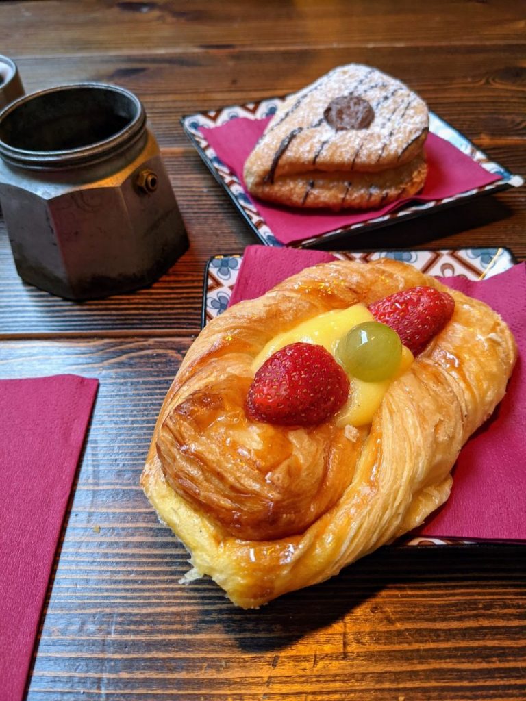 Breakfast pasties: foreground pastry has strawberries, a grape, and cream in the middle; background pastry is chocolate.