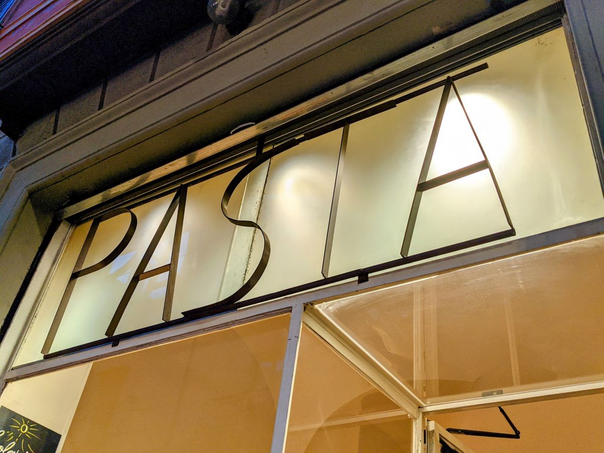 A metal sign outside the restaurant/shop that says "PASTA"