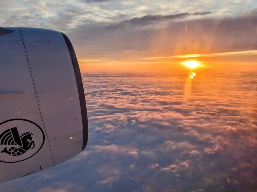 View from the window of our plane as the sun is rising over the clouds