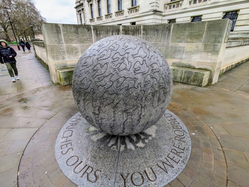 Bali Bombings Memorial. In front is a granite globe covered with 202 dove carvings, and behind the globe is a wall with the names of all 202 victims of the bombine.