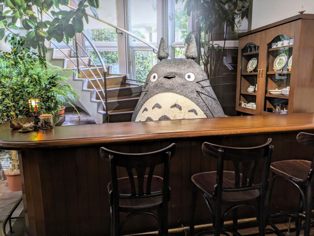 Totoro standing behind a bar at Ghibli Park